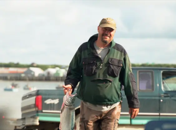 Fisherman on land carrying a wild caught fish